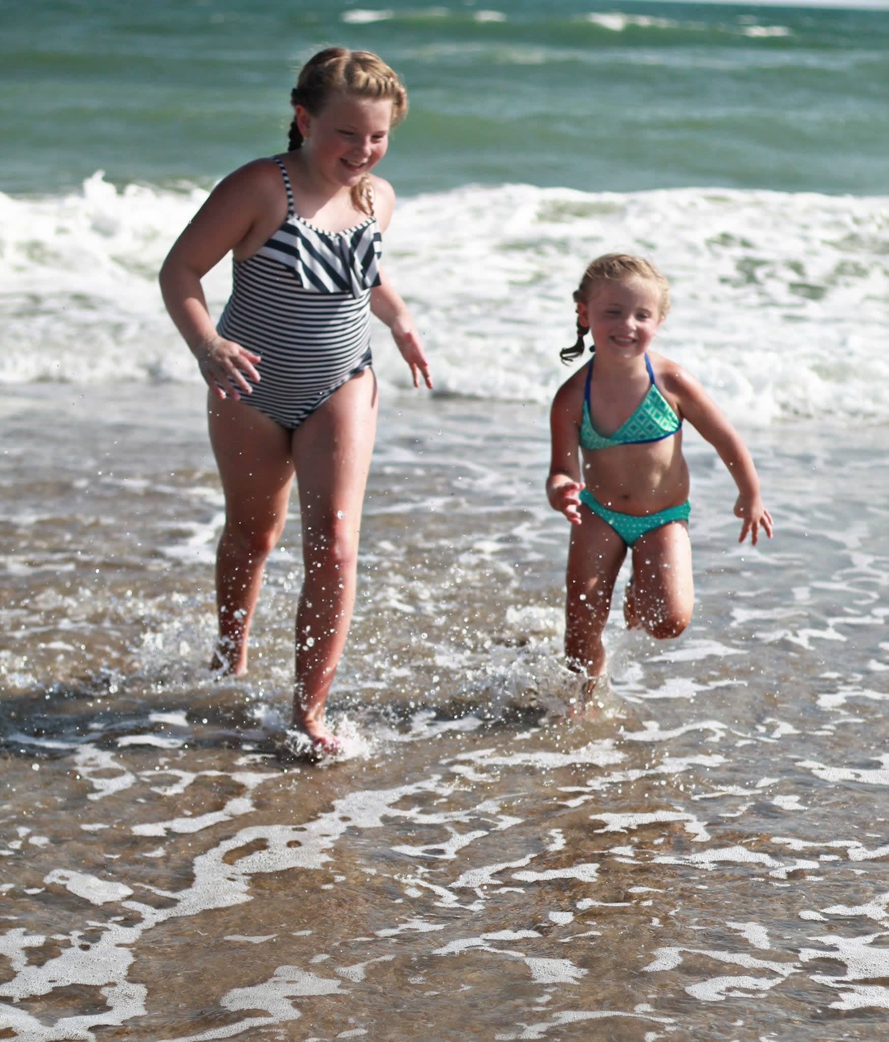 Two little girls running through waves on Holden Beach