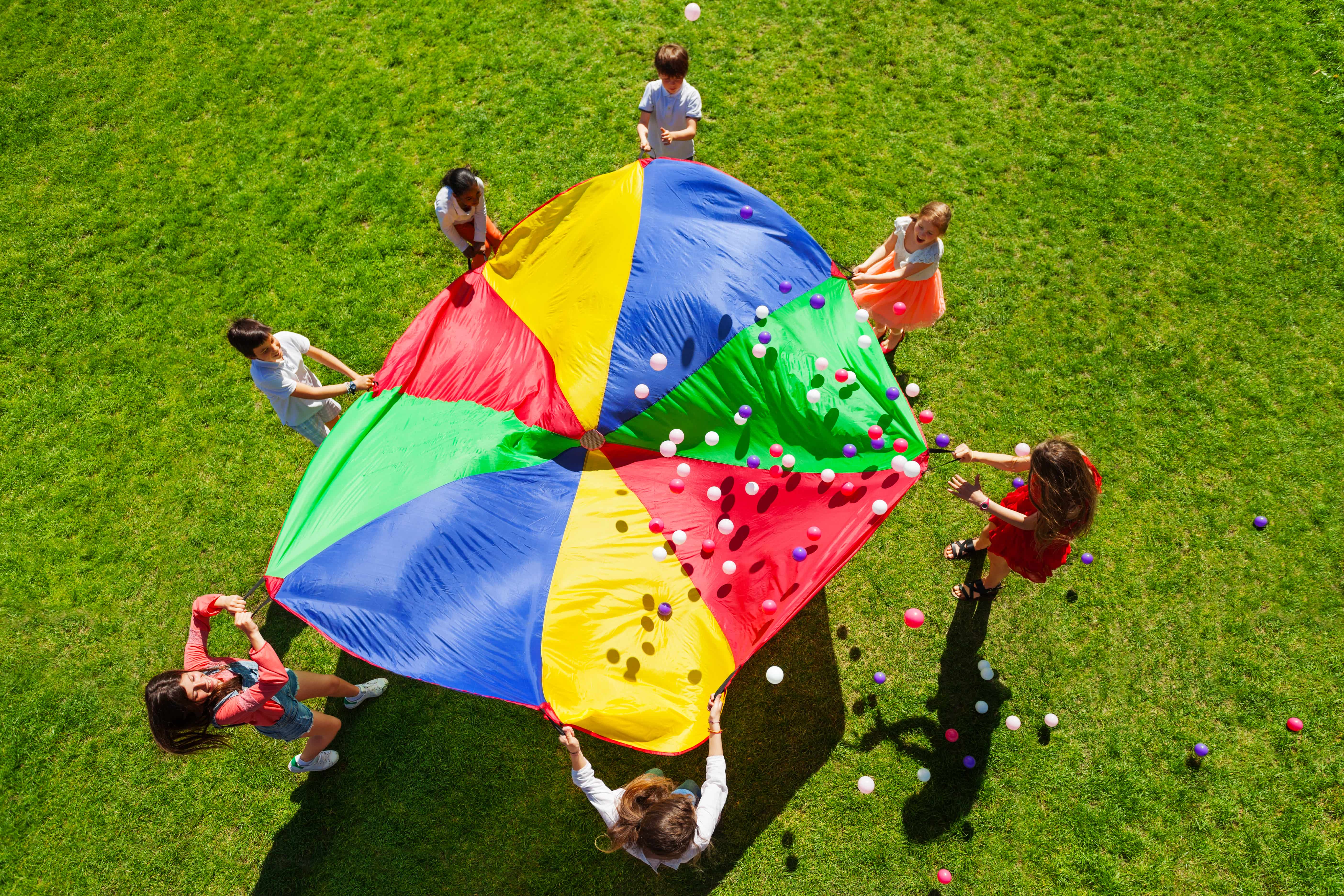 Kids Playing In Grass With Parachute
