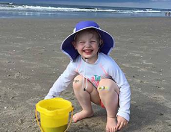Girl smiling on Holden Beach with her bucket