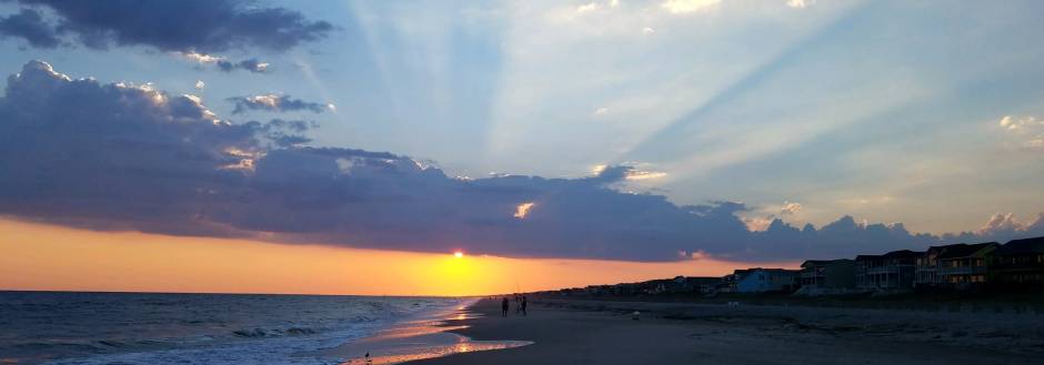 Sun peaking through the clouds at sunset on Holden Beach