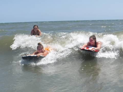Friends riding the wave in on Holden Beach