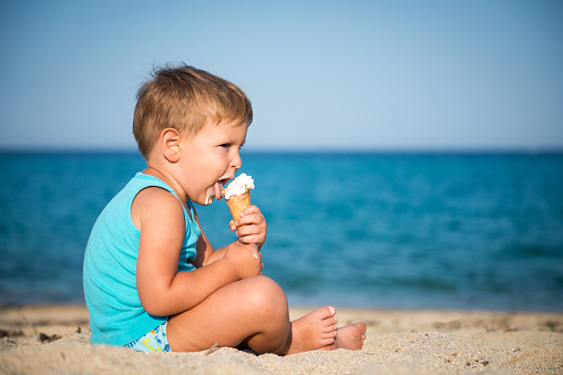 toddler eating ice cream on the beach